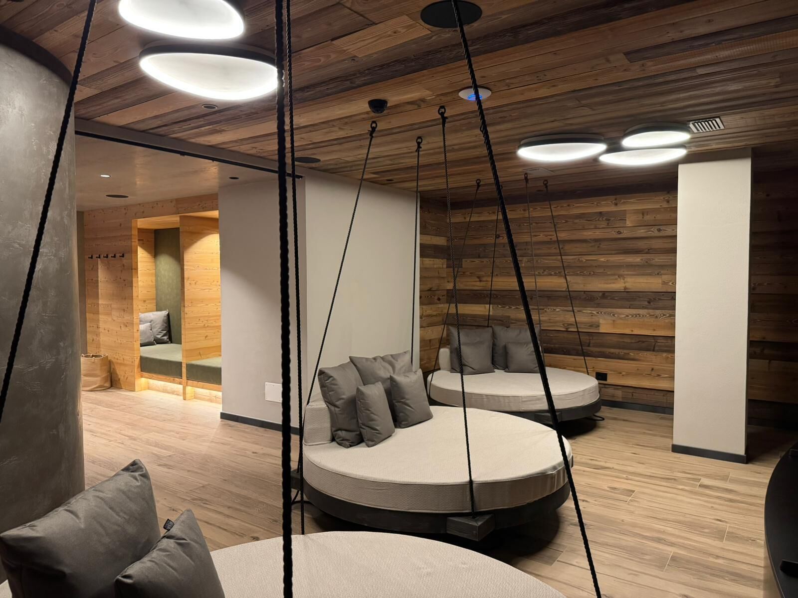 Ein modernes Interieur mit Holzpaneelen, runden Sitzbereichen und hängenden Leuchten.