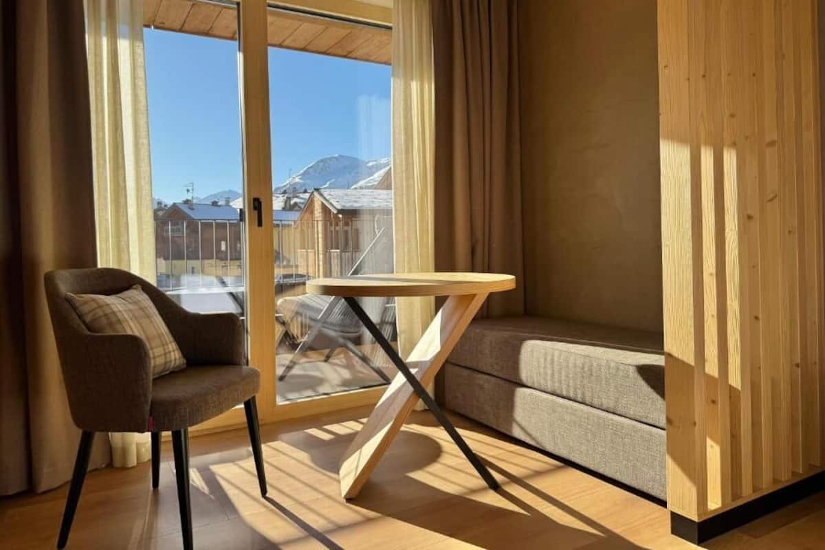 Una habitación moderna con piso de madera, un sofá, una silla y una mesa.