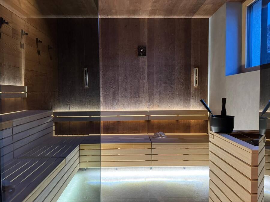 A sauna with wooden benches and a glass partition.