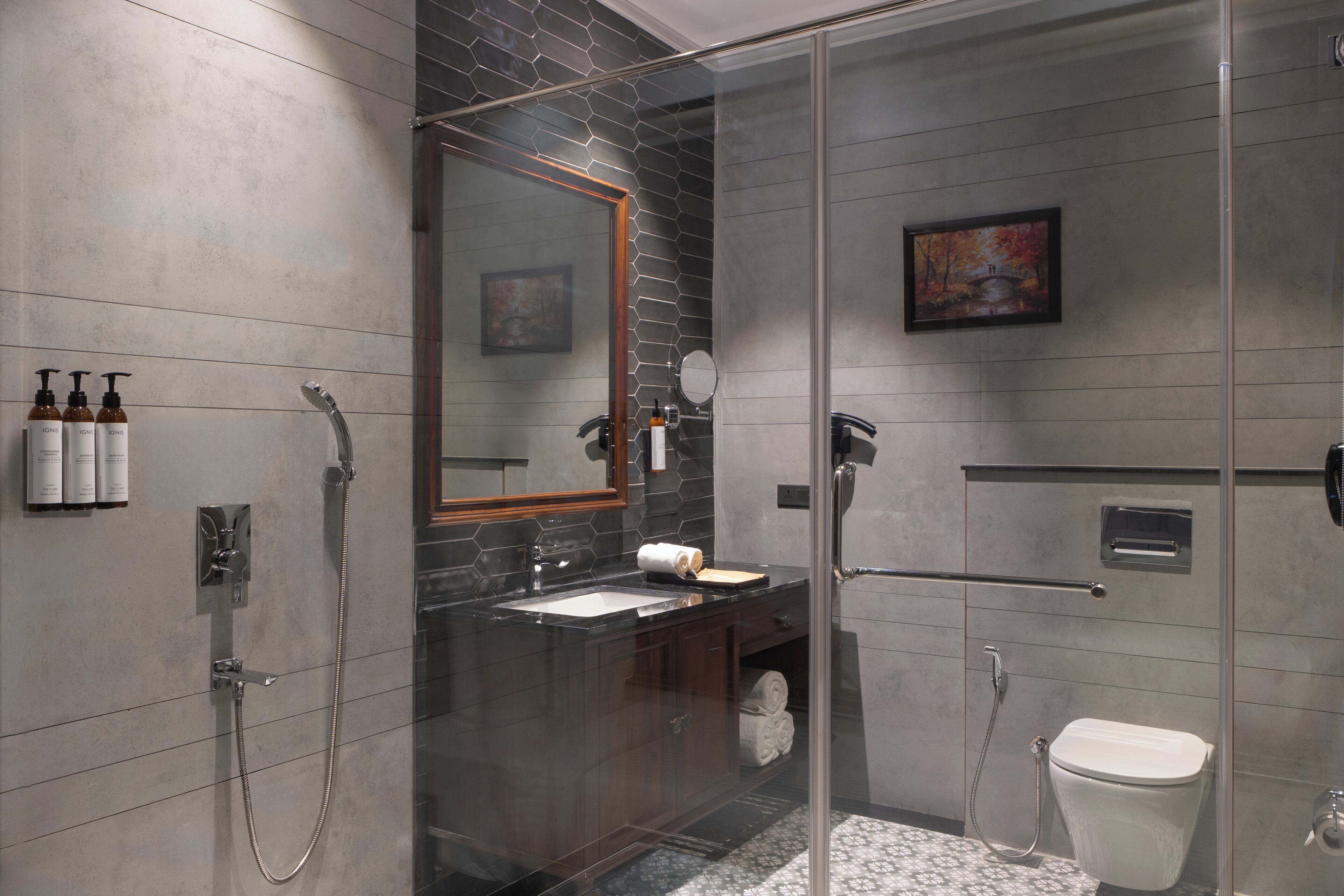 Un baño moderno con ducha envuelta en vidrio, tocador con espejo y retrete.