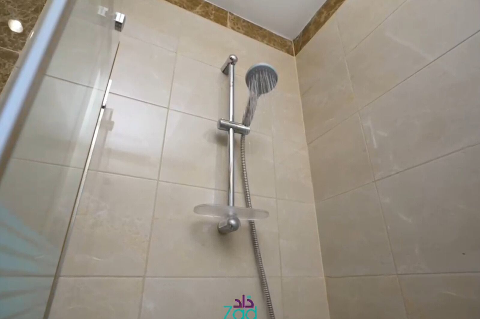 A shower with a handheld showerhead and a wall-mounted faucet.