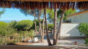 A villa with a thatched roof, surrounded by trees and a view of the landscape. - La Casita - Apartamentos Dos Carneros (Pinos de Alhaurín)