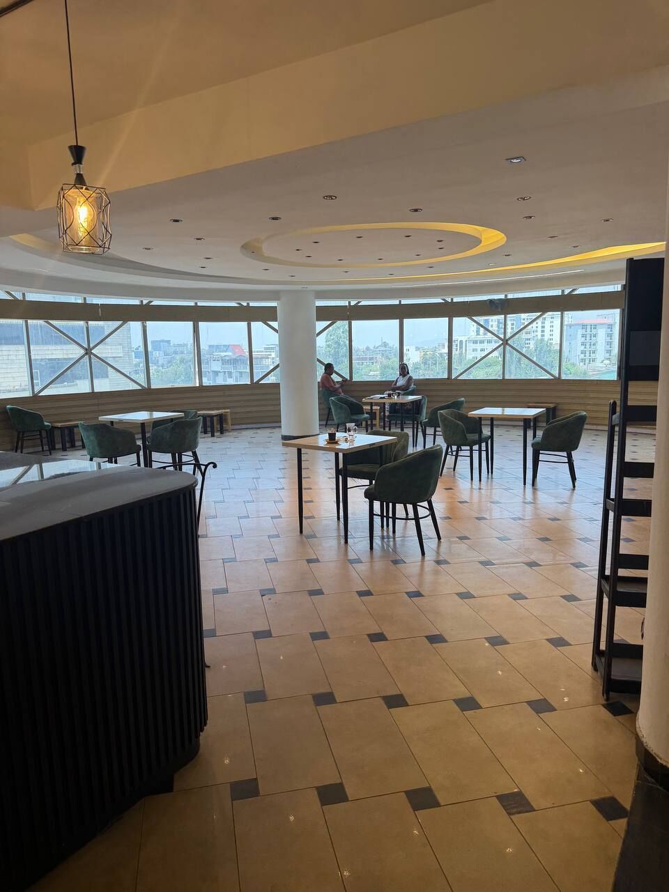 A spacious indoor area with large windows, multiple tables and chairs, and a central counter.