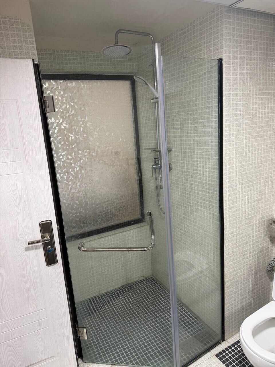 Ein Badezimmer mit Dusche, Toilette und einer Tür.