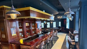 A bar area with a long counter, bar stools, and hanging light fixtures. - Iconic Coworking Hotel (Addis Ababa)