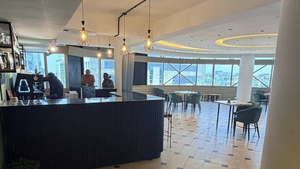 A hotel lobby with a reception desk, seating area, and large windows offering a city view. - Iconic Coworking Hotel (Addis Ababa)