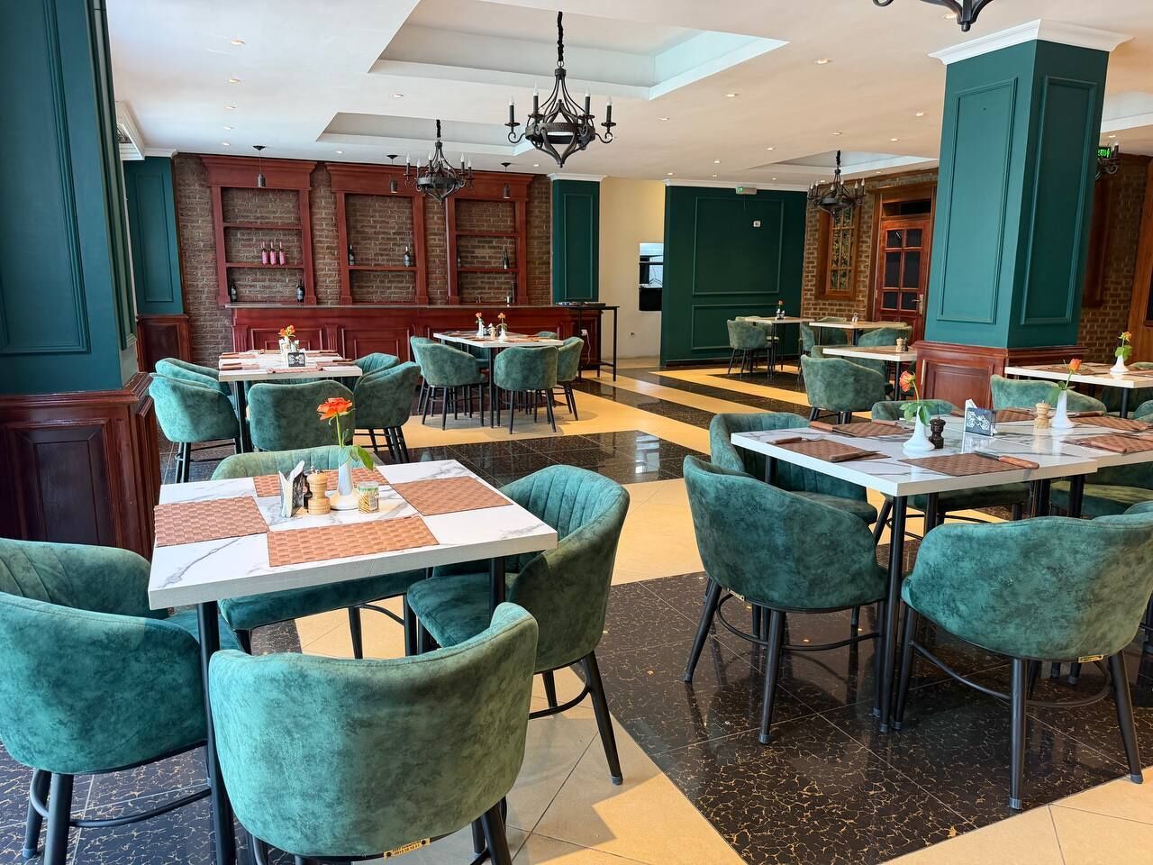 Ein Restaurant mit Türkis-Blauem Stuhl und Tischen, Backsteinwänden und Kristallleuchtern.