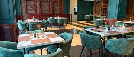 Ein Restaurant mit Türkis-Blauem Stuhl und Tischen, Backsteinwänden und Kristallleuchtern.