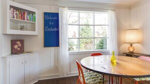A dining area with a round table, chairs, a bookshelf, a window with curtains, and a lamp. - Quiet, 3-bedroom house with calm natural light (Nashville)