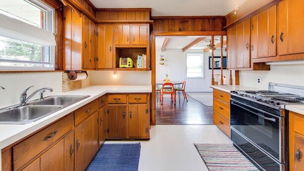 A kitchen with wooden cabinets, a stove, and a dining area with a table and chairs. - Quiet, 3-bedroom house with calm natural light (Nashville)