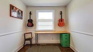 A narrow room with a window, a desk, two guitars, a chair, and a green cabinet. - Quiet, 3-bedroom house with calm natural light (Nashville)