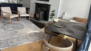Una sala de estar moderna con comedor, chimenea y cocina al fondo.