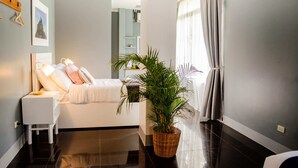 Ein modernes Schlafzimmer mit Bett, Nachttisch und einer Topfpflanze.