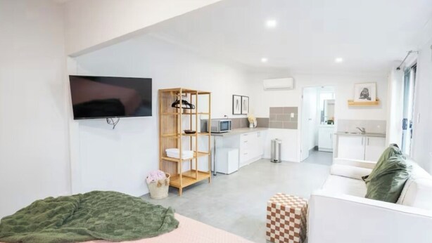 A modern hotel room with a bed, a TV, a kitchenette, a dining area, and a bathroom. - Pink Muse, 3 Mins to Ettalong Beach (Ettalong Beach)