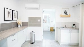 A modern kitchen with white cabinets, grey tiles, and a stainless steel sink. - Pink Muse, 3 Mins to Ettalong Beach (Ettalong Beach)