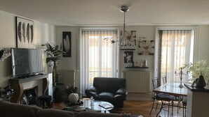 Una sala de estar con sofá, televisión, chimenea, mesa de comedor con sillas y candelabro.