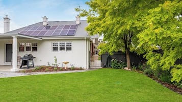 A house with a solar panel roof, a well-maintained lawn, and a black fence.
