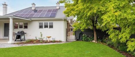 Una casa con un tetto solare, un prato curato e una recinzione nera.