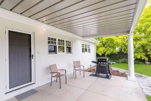 A covered patio with a grill, two chairs, and a door. - Whiterocks Tanunda Walk to Cafés Sleeps 8 Heritage (Tanunda)
