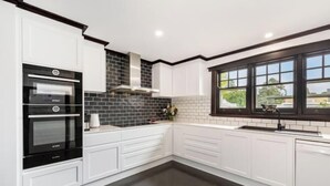 Eine moderne Küche mit weißen Schränken, einem schwarzen Backofen, einer Spritzschutzleiste mit schwarz-weißen Fliesen und einem Fenster mit Blick nach draußen.