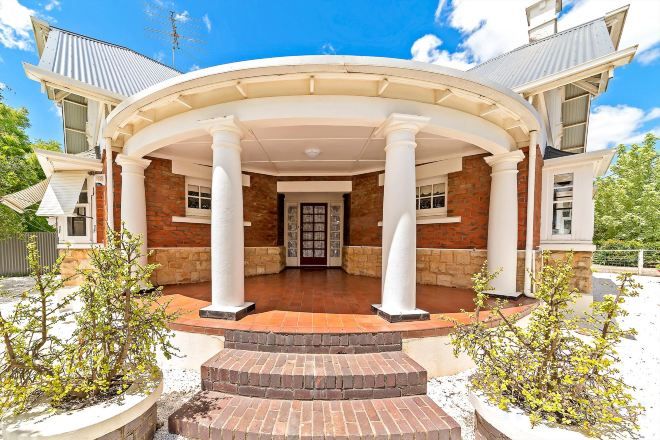 A house with a covered porch, brick walls, and a central door.