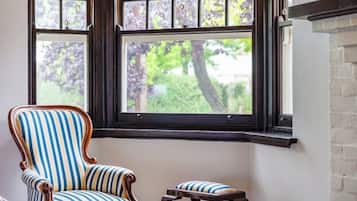 A room with a large window, a striped armchair, and a matching ottoman.