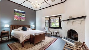 Ein Schlafzimmer mit einem großen Bett, einem Kamin, einem Fenster mit Ausblick und einer Chandelüster.