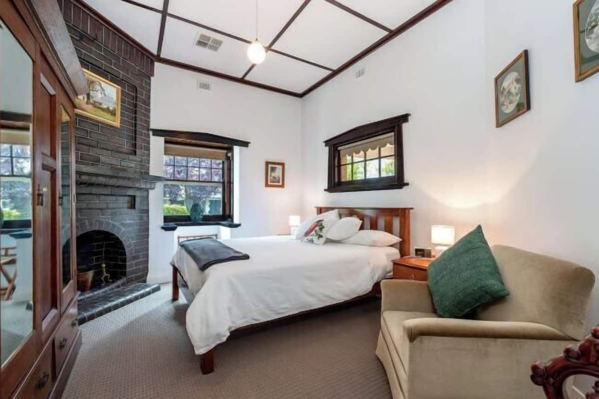Un dormitorio con chimenea, una cama, un sofá y una ventana con vistas.