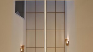 Um interior moderno com escada minimalista, parede com padrão de grade e duas luminárias fixadas na parede.