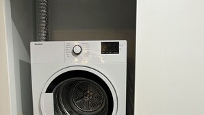 A two-door walk-in laundry room with a wall-mounted dryer and a front-loading washing machine. - Infinite blue (Vancouver)
