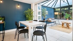 Ein Essbereich mit einem weißen Tisch und schwarzen Stühlen, umgeben von blauen Wänden und großen Fenstern.