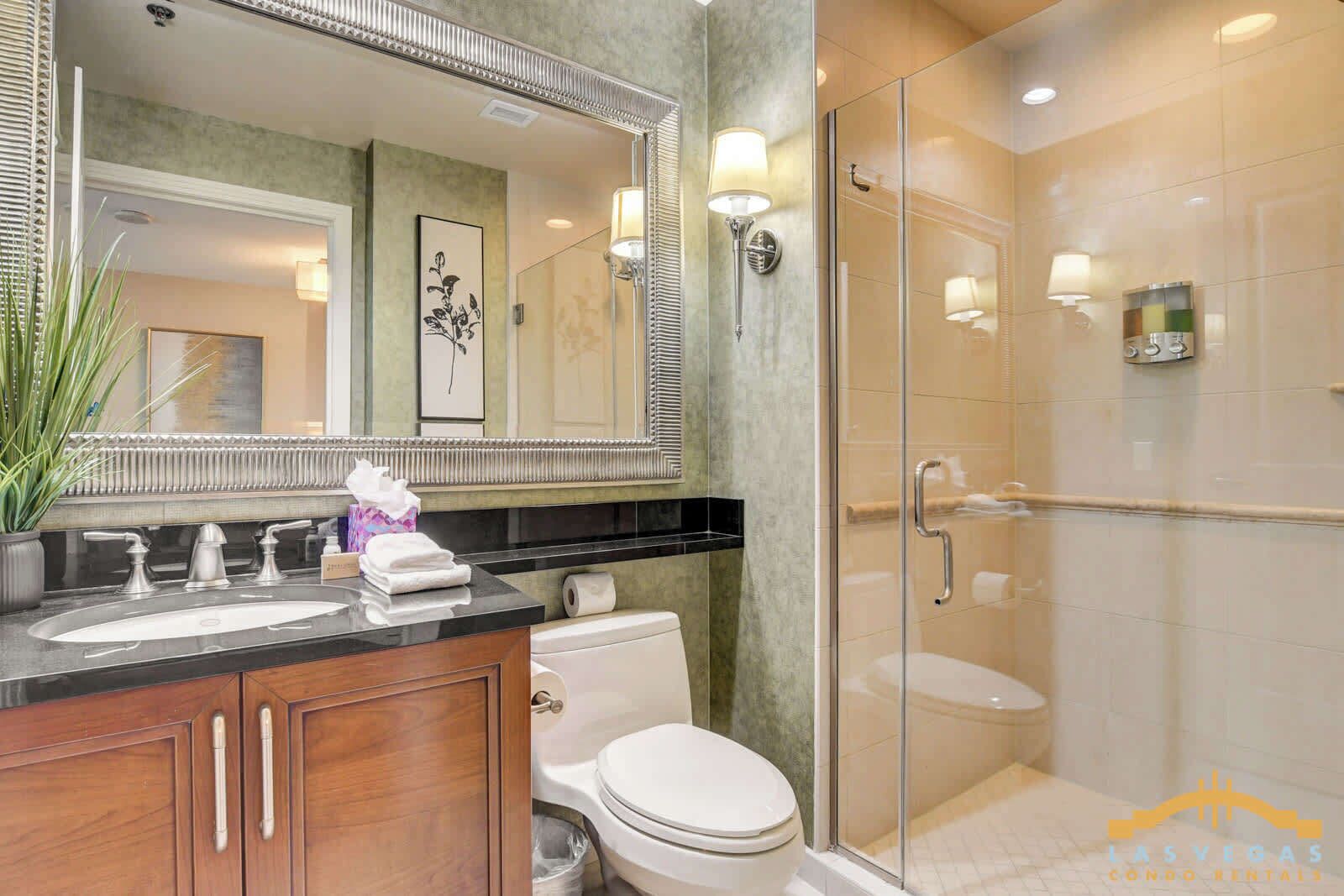 A modern bathroom with a glass-enclosed shower, a large mirror, and a vanity with a sink and towel rack.