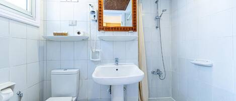 A small, clean bathroom with a toilet, sink, and shower.