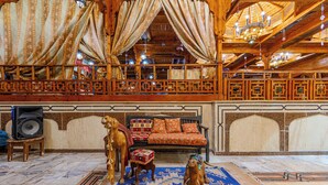 Une pièce avec un plafond en bois, une moquette à motifs, un canapé avec des coussins et une statue de chameau.