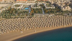 Vue aérienne d’une plage avec de nombreux parasols et un espace piscine.