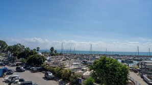 A marina with boats docked, a parking area, and a clear view of the sea. - Dar Elyssa (Sidi Bou Said)