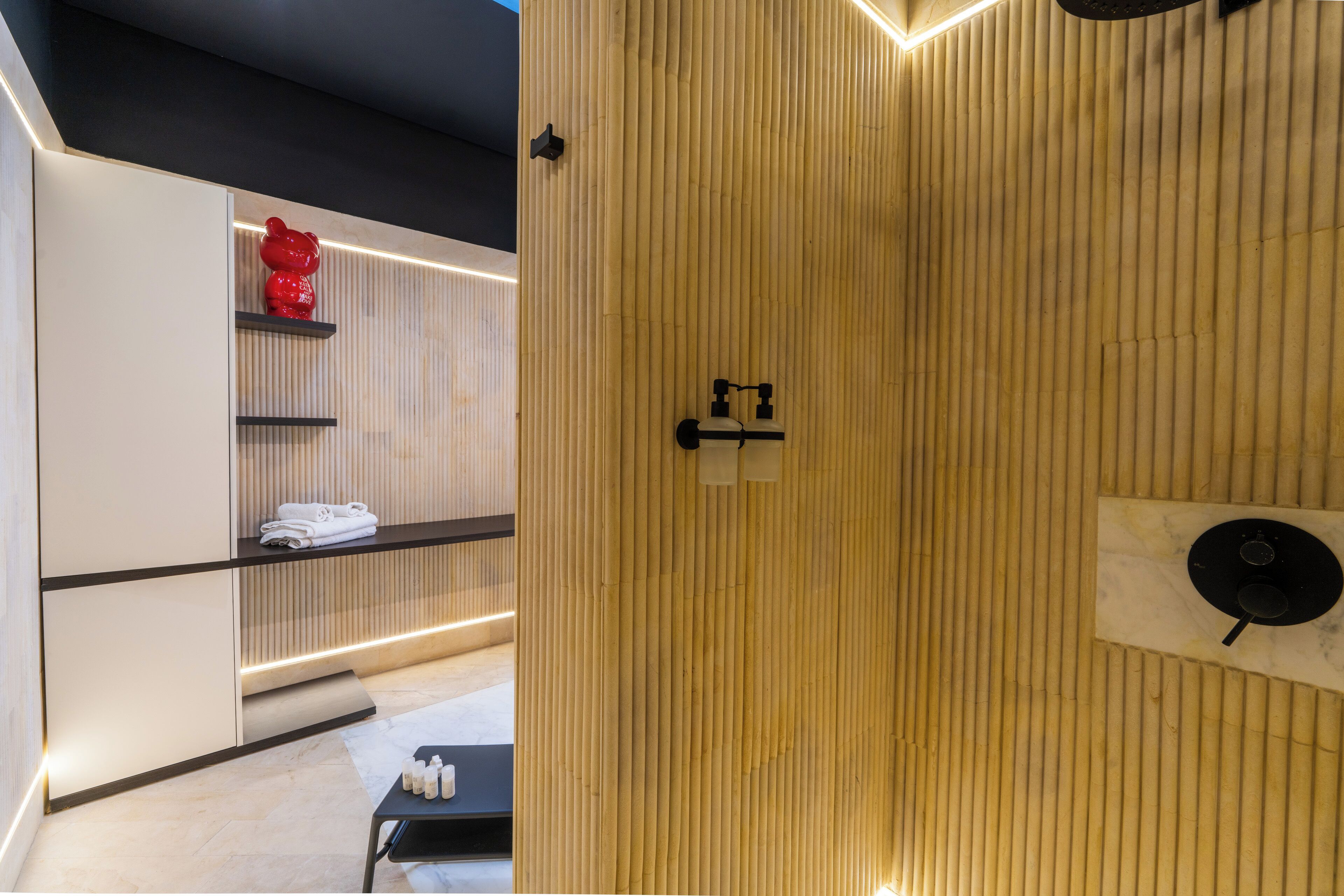 A modern bathroom with a wooden panel wall, a red decorative item on a shelf, and a black towel rack.