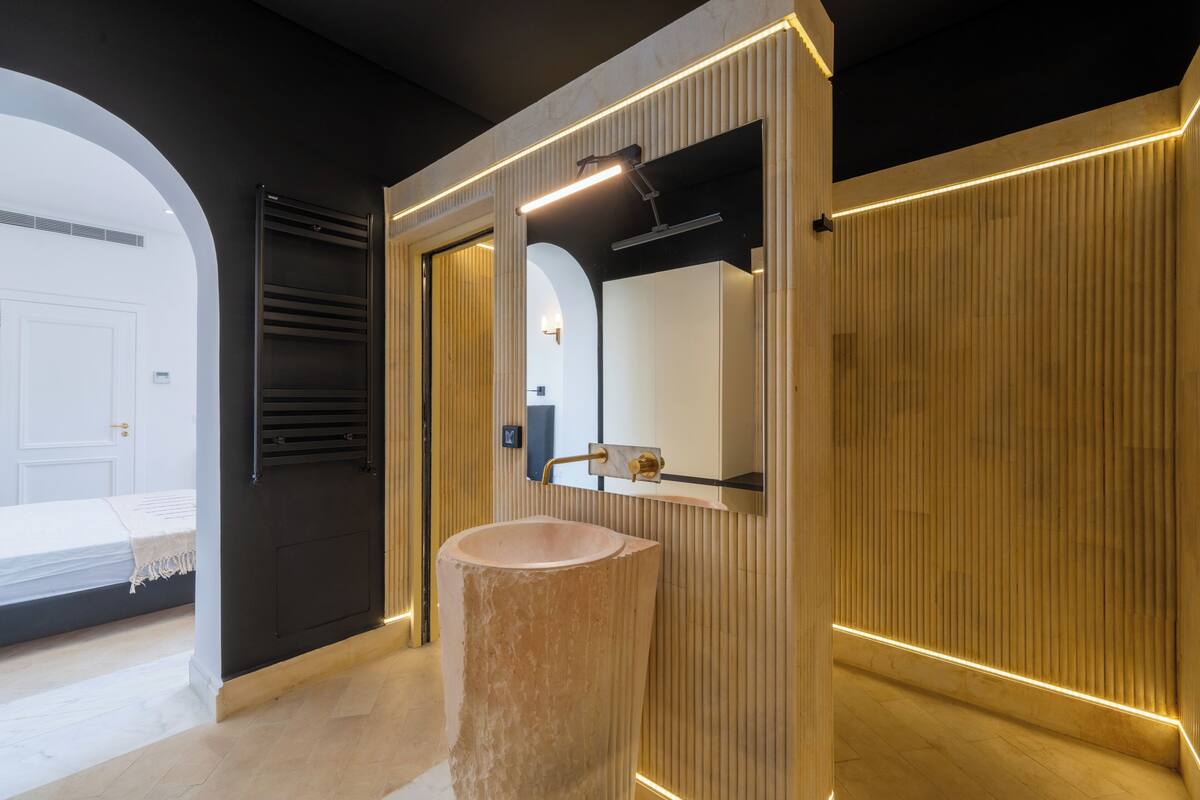 A modern bathroom with a large, round sink, a mirror, and a towel rack.
