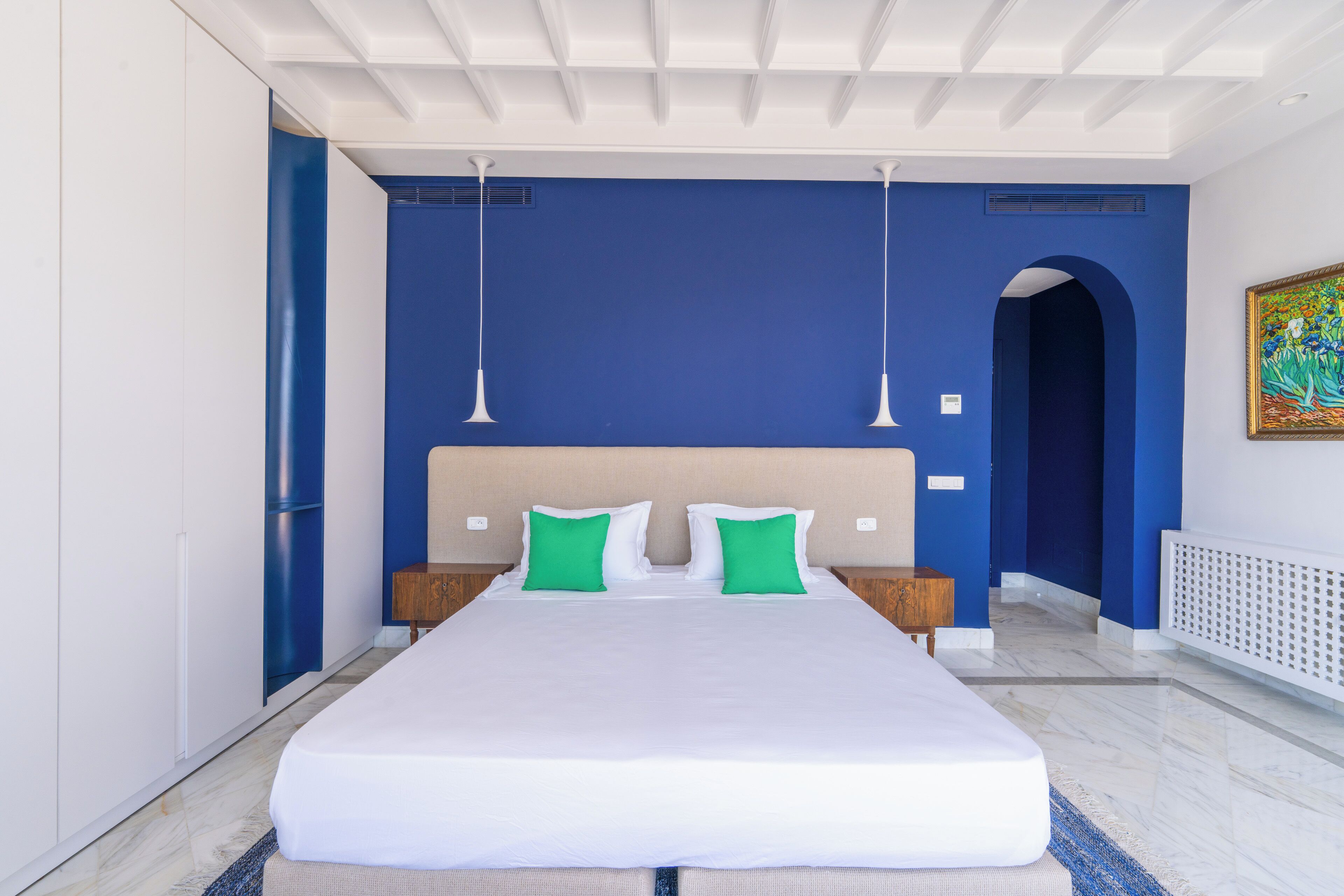 Un dormitorio moderno con una cama grande, paredes azules y un techo blanco.