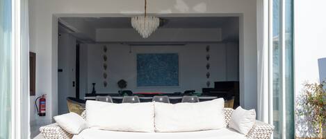 Un salón tipo loft con un sofá blanco estampado, una araña de cristal y un cuadro abstracto azul en la pared.