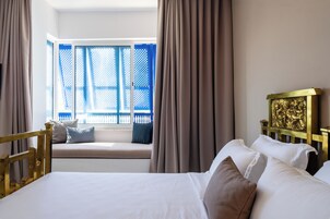 Una habitación de hotel con cama, un asiento junto a la ventana y cortinas.