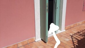 A white chair outside a building with a green door. - 🏡 Panoramic House in Cassone - Renovated Apartment with Lake View (Malcesine)