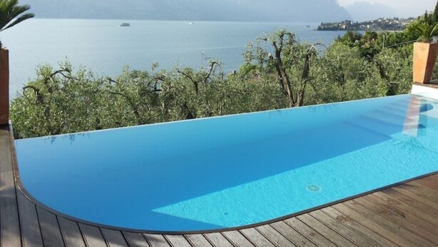 A swimming pool with a view of a lake and mountains. - 🏡 Panoramic House in Cassone - Renovated Apartment with Lake View (Malcesine)