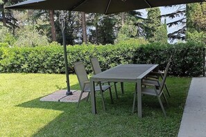An outdoor patio with a table and chairs under a canopy. - The Essence of Apartment No. 1—Relaxation and Comfort in the Heart of Malcesine (Malcesine)