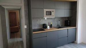 Een moderne keuken met grijze kastjes, een houten aanrechtblad, een ingebouwde magnetron en een koffieapparaat.