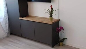 Een moderne kamer met een houten bureau, grijze kastjes en een potplant.