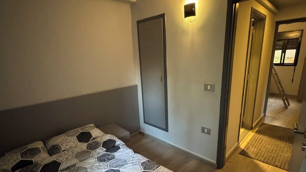 Un dormitorio moderno con una cama grande, un armario y una pequeña lámpara de pared.