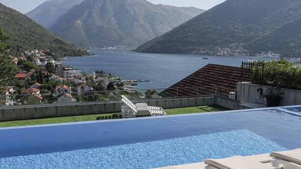 A swimming pool with lounge chairs, a view of a lake, and mountains in the background. - The house is our passion project, built with love surrounded by forest and views (Kamenari)