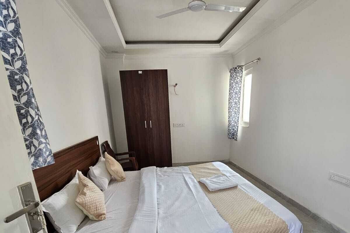 A bedroom with a bed, a wardrobe, a ceiling fan, and a window with curtains.