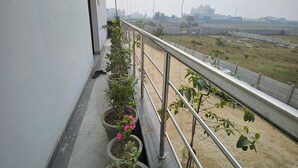A balcony with potted plants and a view of a distant building. - Ram Darshan Palace (Tarabganj)